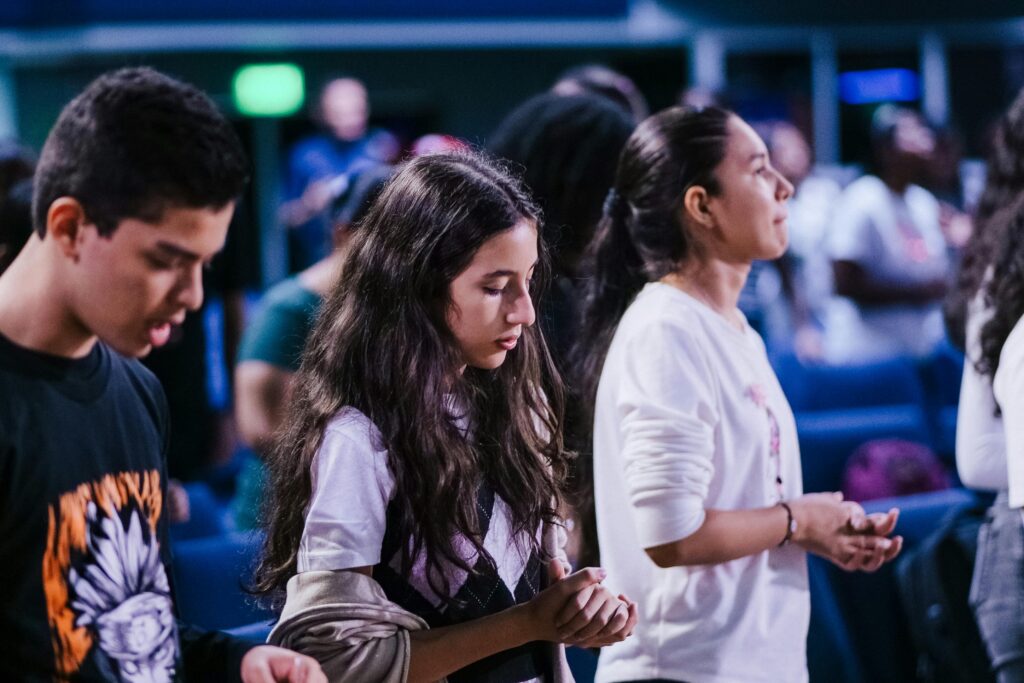 A group of young individuals deep in prayer during a church service.