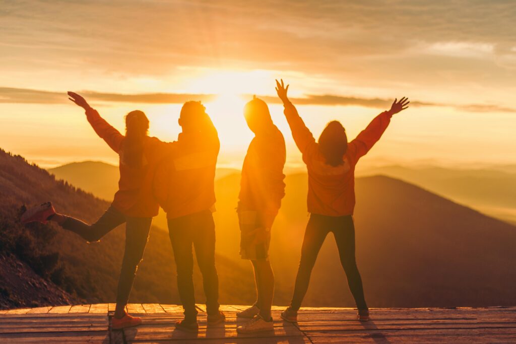 Silhouetted group of adults celebrating at sunset.