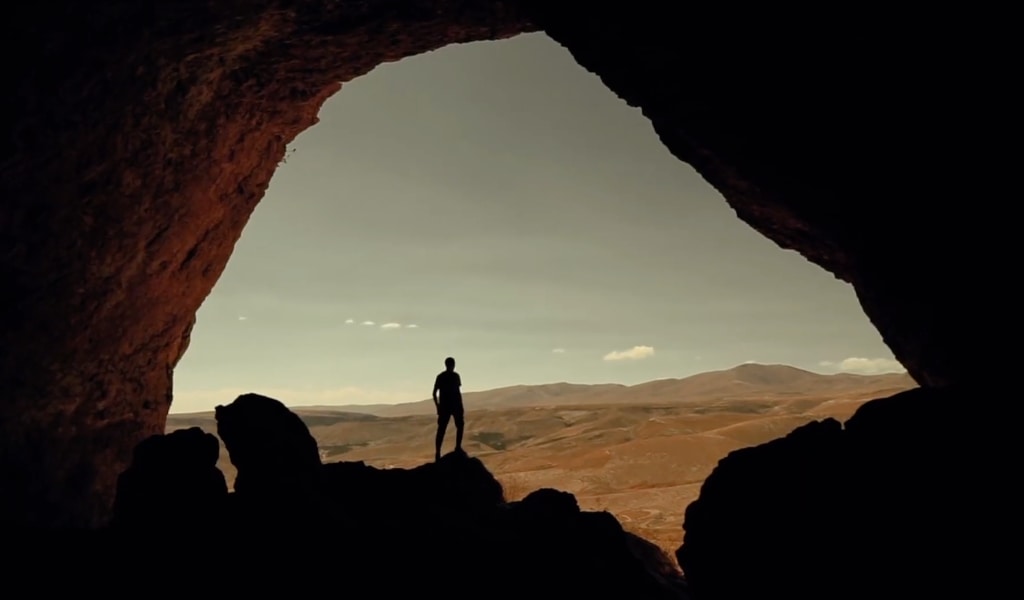 A man standing at a cave entrance.