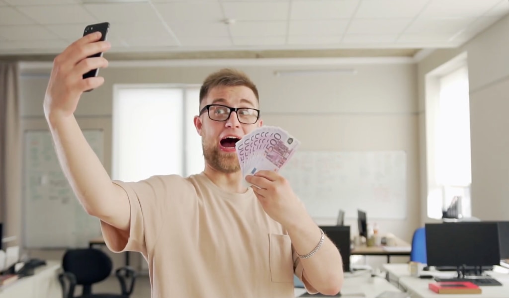 A man taking a selfie with a lot of cash.